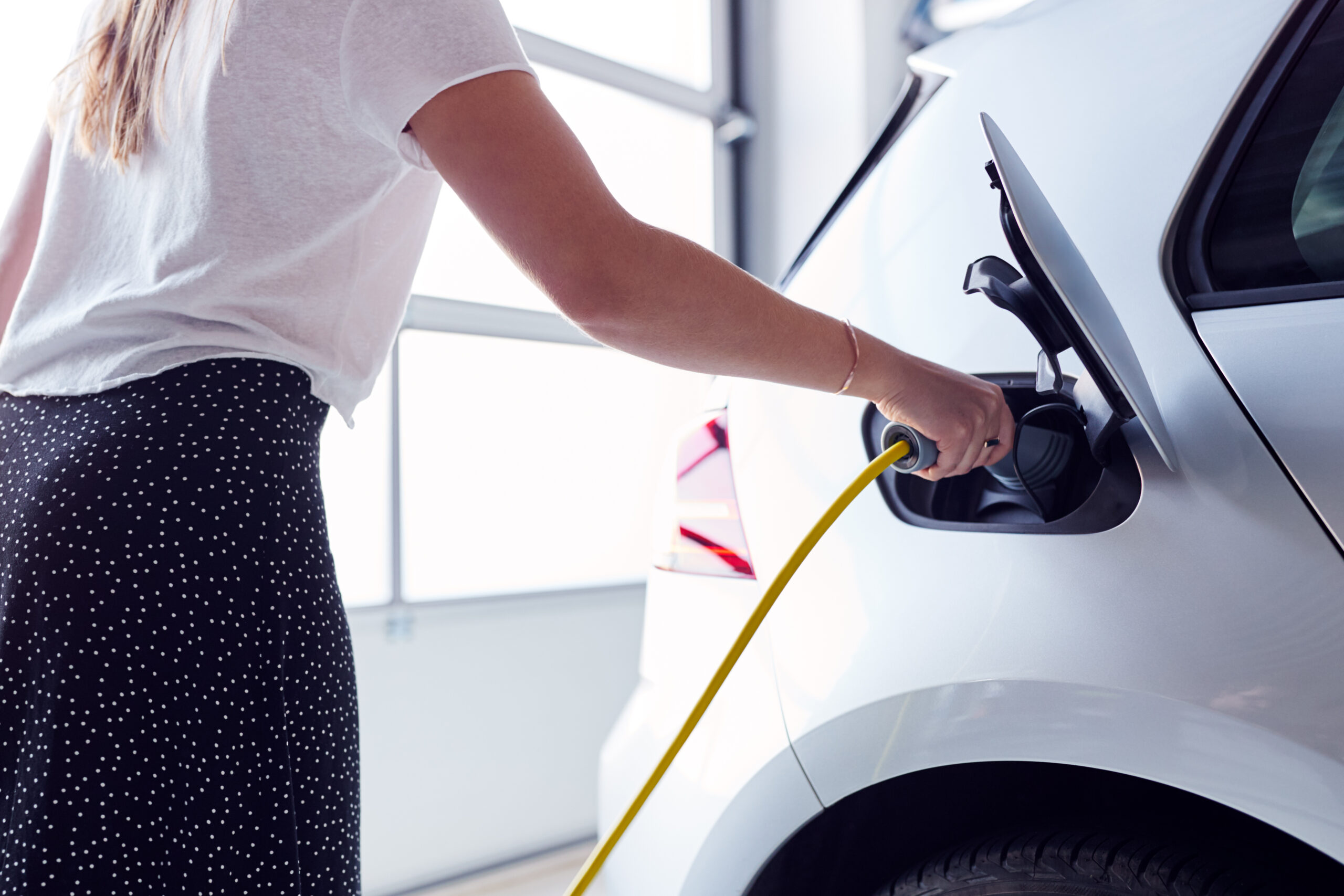 A woman is holding the hose to fill up her car.