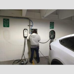 A man is charging his electric car in the garage.