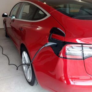 A red car is plugged into an electric charger.
