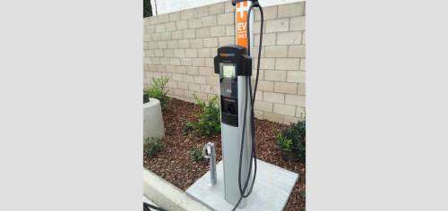 A charging station for electric vehicles in front of a brick wall.